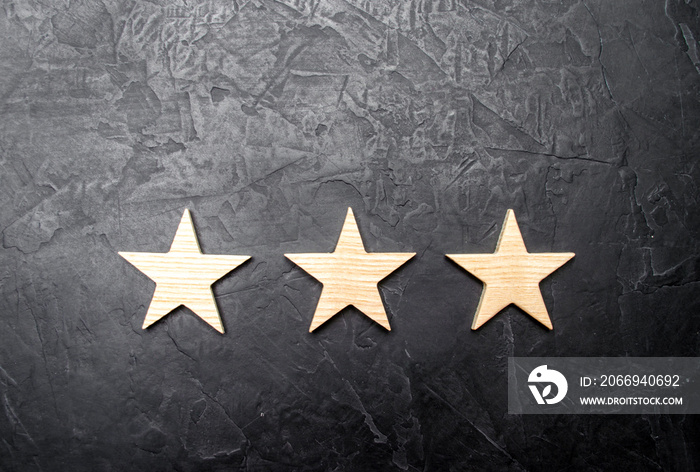 Three stars on a dark background. The concept of rating and evaluation. The rating of the hotel, restaurant, mobile application. Quality service, buyer choice. Success in business