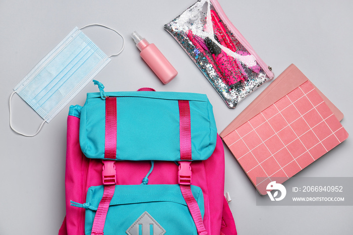 School backpack, stationery, sanitizer and medical mask on white background