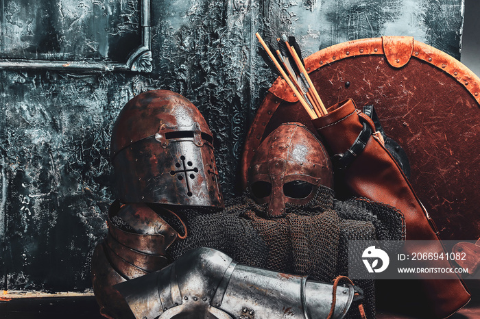 Still life with ancient shield, two rusted helmets, quiver of arrows and chain mail.