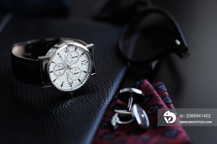 Luxury men’s watch with cufflinks, breastplate and sunglasses close up.