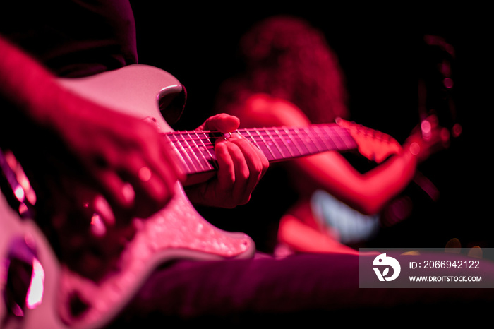 guitarist plays the electric guitar, close-up of the guitar and hands, red lighting