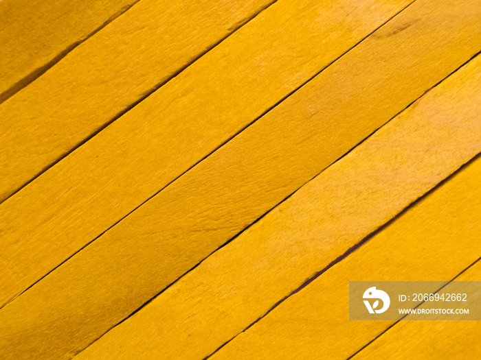 Background of yellow popsicle sticks with diagonal view.