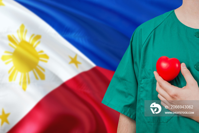 Philippines veterinary clinic concept. Veterinarian is holding plastic heart in green uniform on national flag background. Animial love theme.