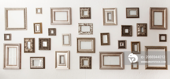 Multiple many blank small picture frames on white wall