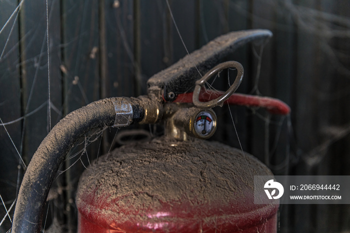 old fire extinguisher covered with dust and cobweb