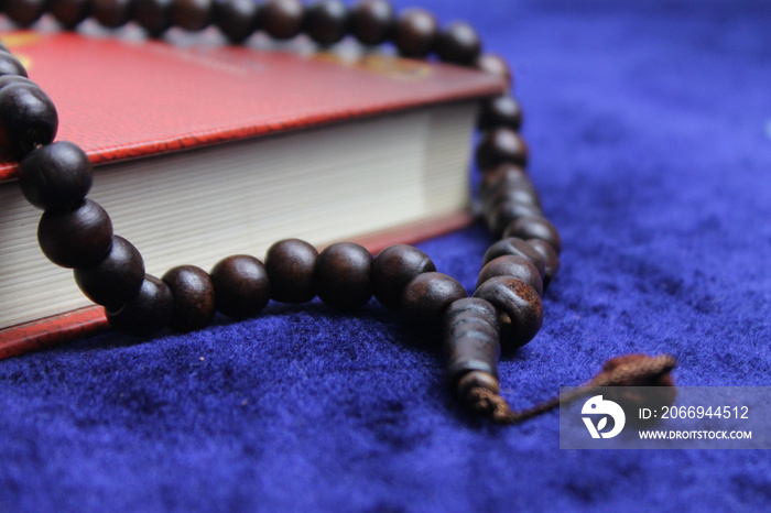 Close up Holy Quran with tasbih or muslim beads rosery over a praying mat. Ramadan Kareem