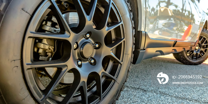 Black tire rim and disc brake of a shiny white car