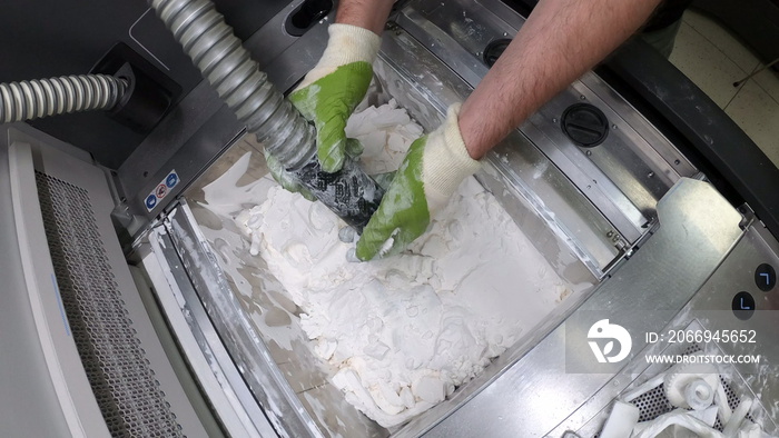 Man cleans details printed on industrial 3D printer from white plastic powder. Automated additive technologies. Person cleans vacuum cleaner plastic powder from models printed on 3D printer.