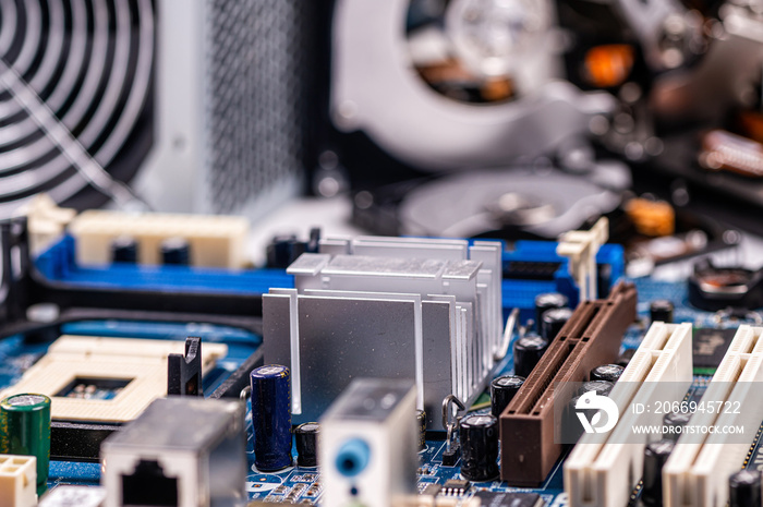 part of computer circuit board with components on the background of defocused power supply fans, close-up