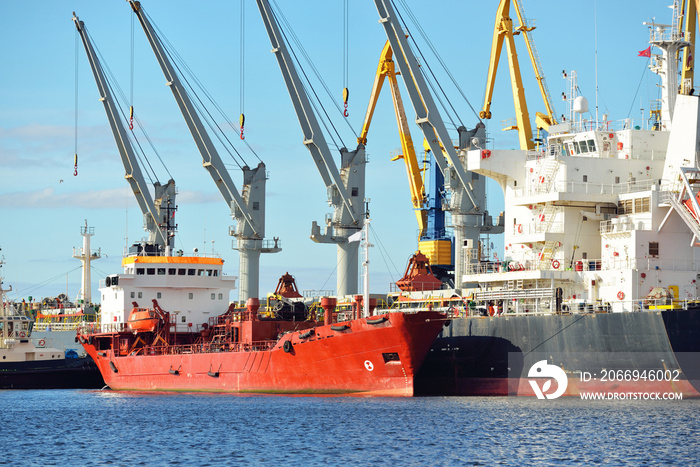 Cargo ships loading in port terminal. Cranes in the background. Baltic sea. Bunkering, fuel and power generation, supply, technology, logistics, service, industry, business, commerce