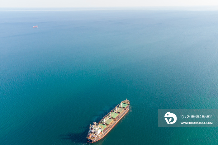 The dry cargo vessel enters the port with the help of tugs. Photo from a helicopter. Bird’s-eye view.