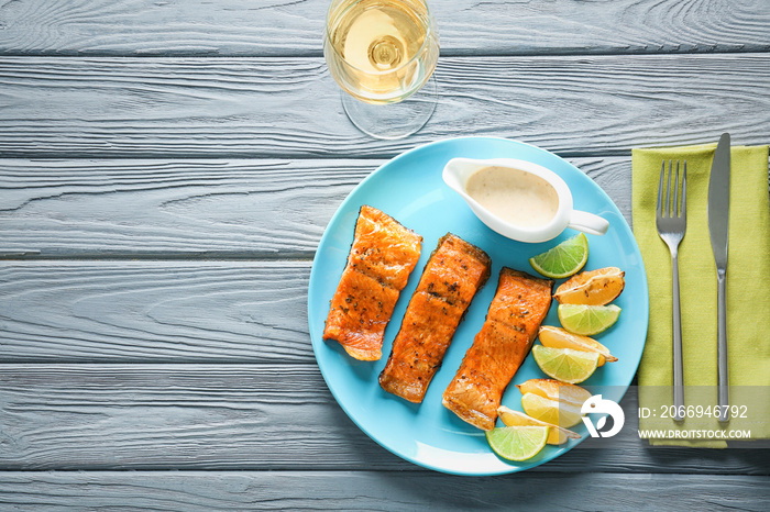 Delicious fried rainbow trout with lime, lemon and sauce on plate, top view