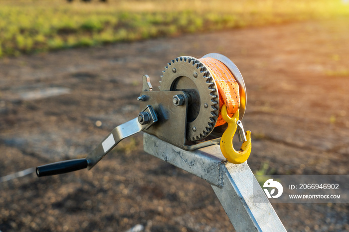 Boat trailer winch close-up, small metal mechanical wire yellow rope winch with a stainless steel hook