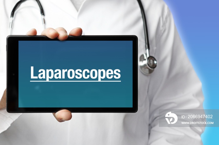 Laparoscopes. Doctor in smock holds up a tablet computer. The term Laparoscopes is in the display. Concept of disease, health, medicine