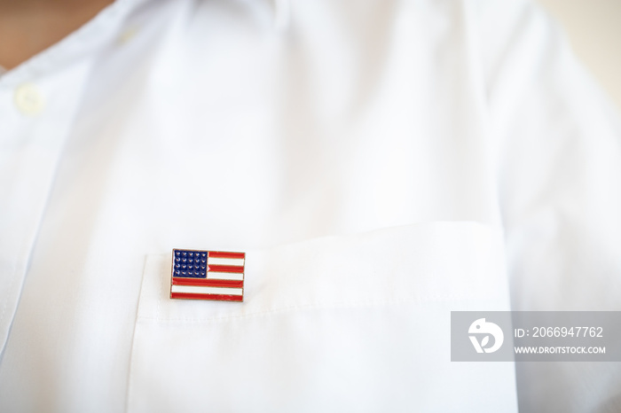 Close up of United State of America pin national flag on white shirt pocket.