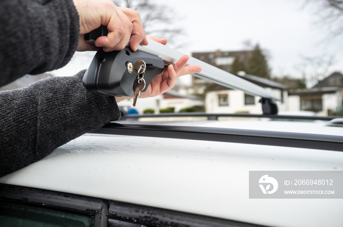 Man installs attachments with a lock and keys for the trunk or cargo box on the roof of a car.