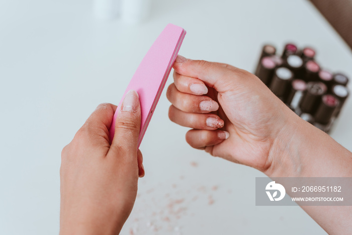 Maniküre der Fingernägel mit Feile. Junge Frau macht schöne Nagelpflege vor Füllung mit Acryl