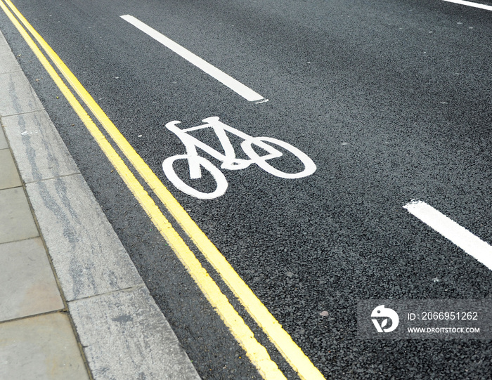 Cycle lane with bicycle symbol on asphalt in the streets of London, UK. Ecological and sustainable transport. Energy saving. White bike icon on black asphalt texture. Urban scene