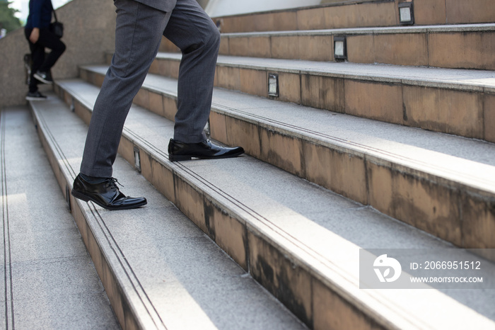 Business and grow up concept. Close up legs business man holding briefcase and walking up stairs going to work at morning in the city.