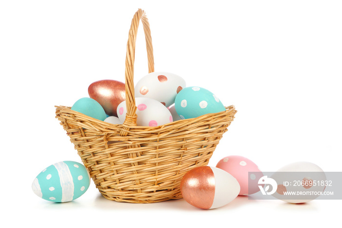 Easter basket filled with colorful hand painted pink, blue, white and rose gold Easter Eggs isolated on a white background