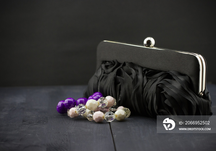 The black woman’s handbag and bracelets of beads on dark wooden background