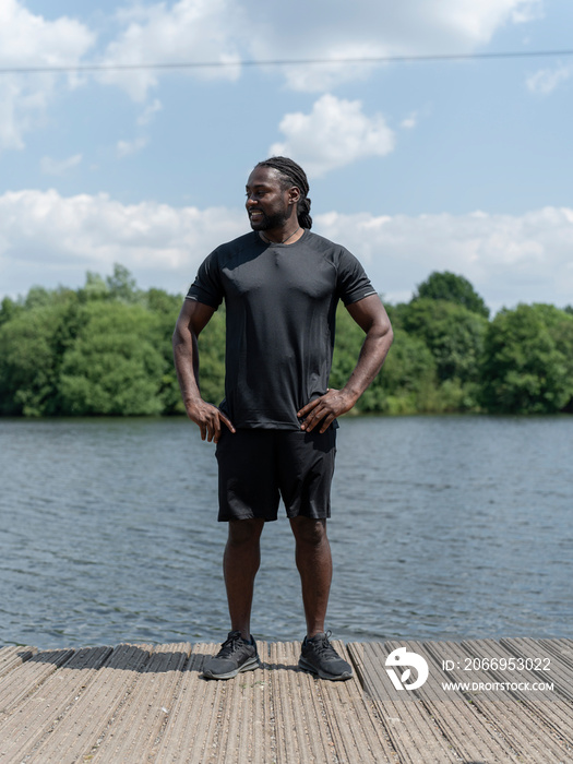 Muscular man in sports clothing standing by lake