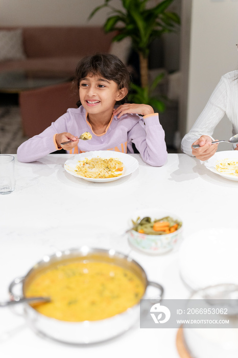 Little girl eating meal at table