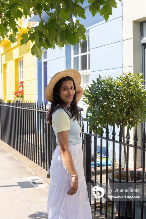 Portrait of smiling young woman in sun hat standing in street