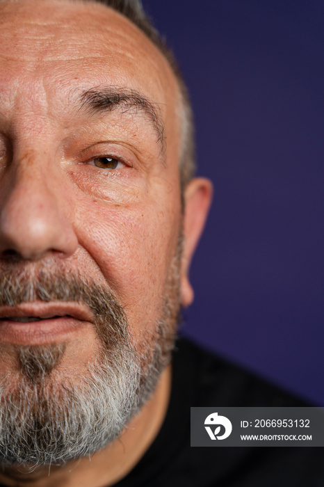 Portrait of serious man with beard against purple background