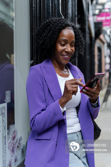 Smiling woman using smart phone in city