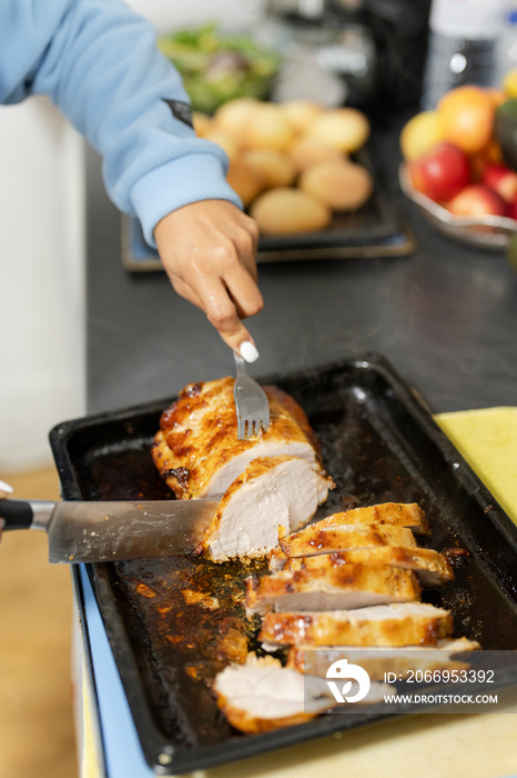 Woman slicing cooked meat on kitchen counter, close up