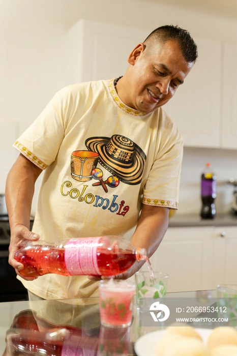 Man in domestic kitchen pouring soda into glasses