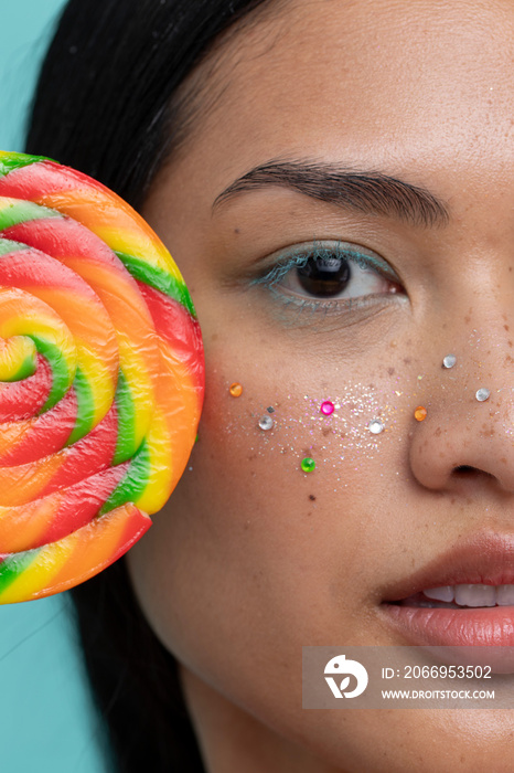 Woman holding colorful lollipop in front of face