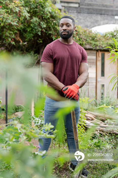 Portrait of smiling man standing in urban vegetable garden