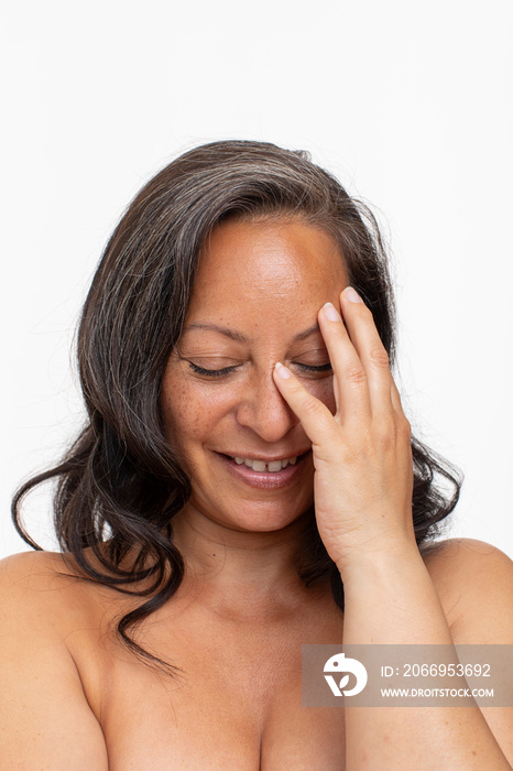 Studio portrait of smiling shirtless woman with eyes closed touching face