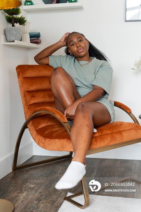 Portrait of young woman looking at camera while sitting in armchair at home