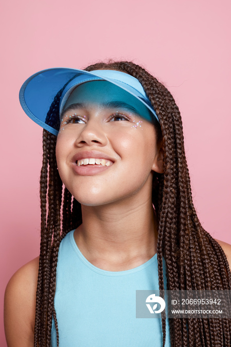 Studio portrait of smiling girl wearing sun visor