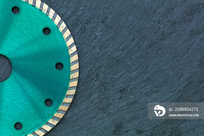 A part of the diamond cutting wheel of emerald color against the background of gray granite.