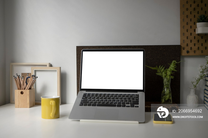 Mock up computer laptop, Coffe cup, houseplant, smart phone and pencil holder on white desk.