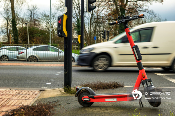 Battery powered electric scooter vehicle left on pedestrian footpath near motorway in england uk