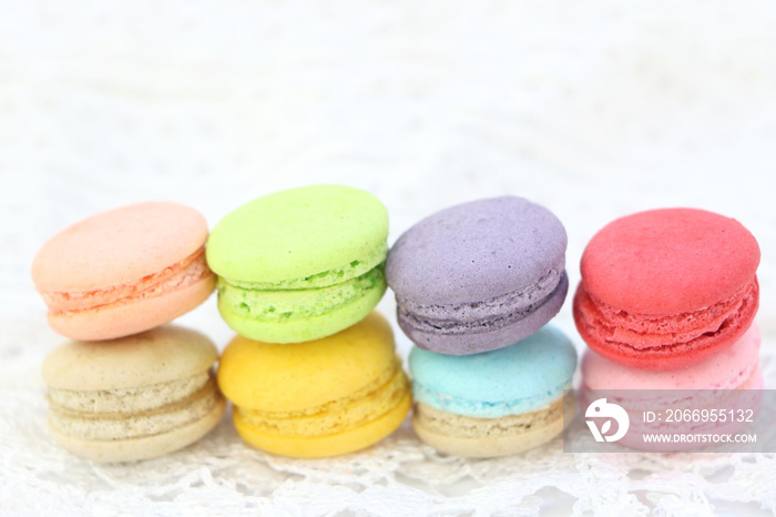 Close up colorful fresh sweet cake macarons stack horizontal line on white fabric background, have copy space for put text.