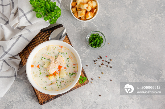 Salmon soup with cream, potatoes, carrots, herb and croutons in a bowl on a gray concrete background. Copy space.