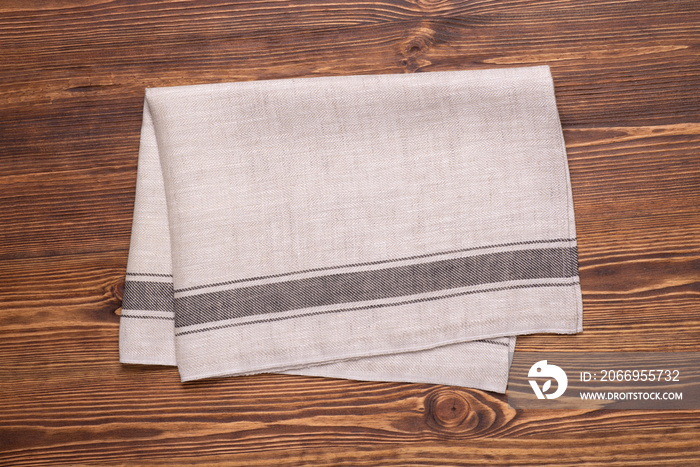 Kitchen towel or napkin on brown rustic wooden table top. Mock up for design. Top view