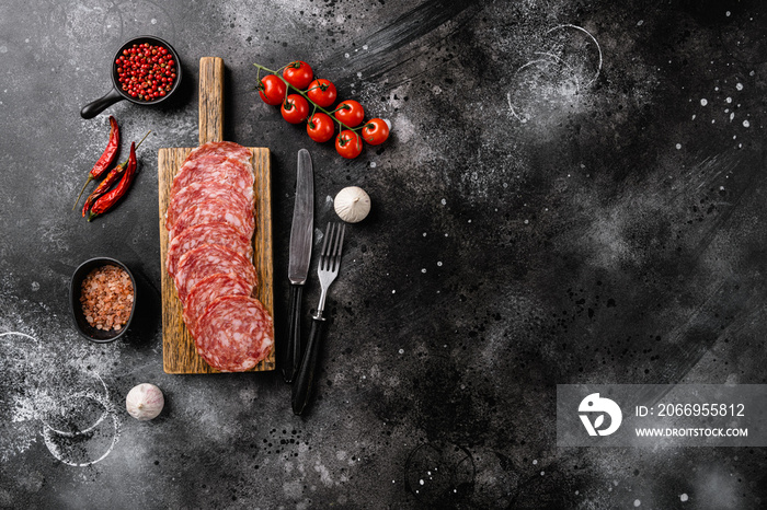 Salami Milano sliced sausage, on black dark stone table background, top view flat lay, with copy space for text