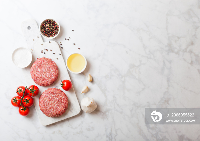 Raw minced home made grill beef burgers with spices and herbs. Top view with space for your text on marble background