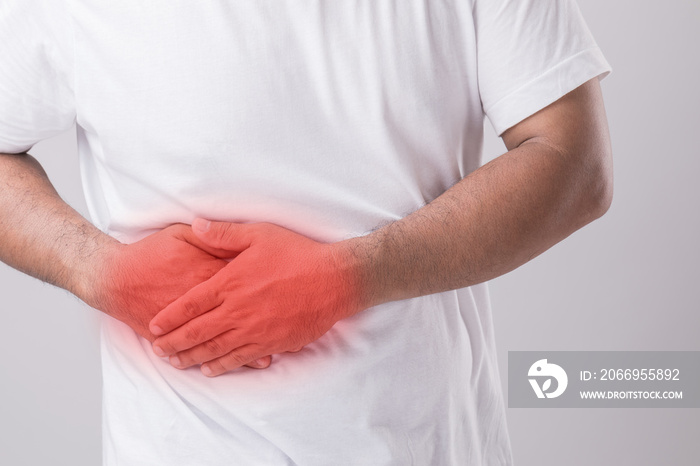 Liver or kidney problem concept : Man holding hand on belly and feeling a pain in liver or . Studio shot isolated on grey background with copy space for text