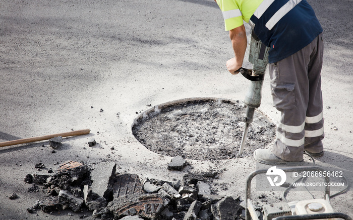 jackhammer in the hands of asphalt worker preparing logs underground