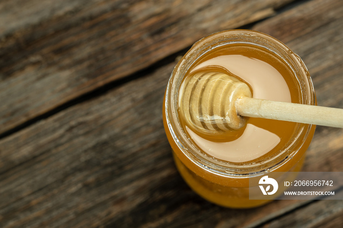 Honey jar and wooden spoon in jar. Bees produce fresh, healthy, honey. Honey background. Beekeeping concept