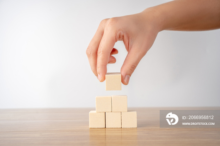 Hand putting and stacking blank wooden cubes on table with copy space.