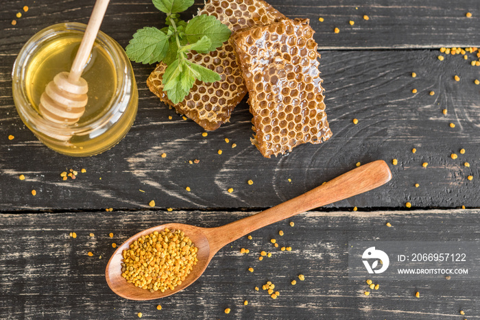 Beautiful transparent honey in bank, honeycombs and pollen on a wooden table. It can be used as a background